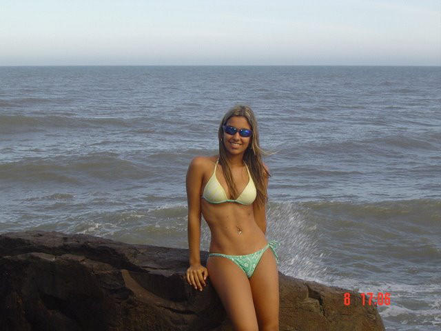 Hot babe in bikini stands on a rock