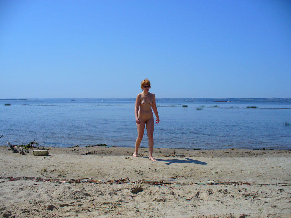 Naked girl taking photo on a sandy beach