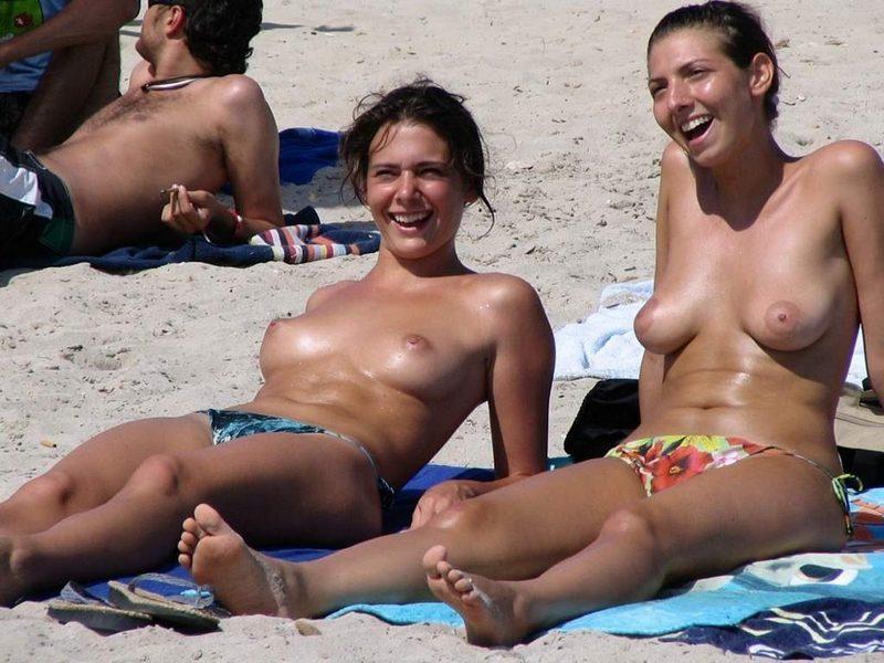 Hot topless chicks sharing a joke at the beach