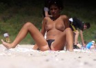 Brunette sunbathing topless on the beach