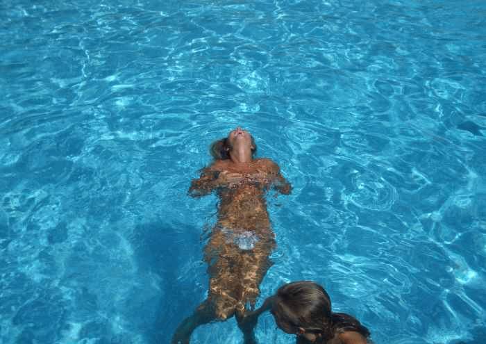 Naked beauty swimming topless in the pool