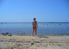 Naked girl taking photo on a sandy beach