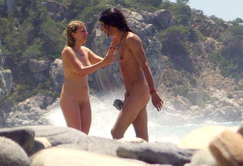 Naked couple showing affection on the beach